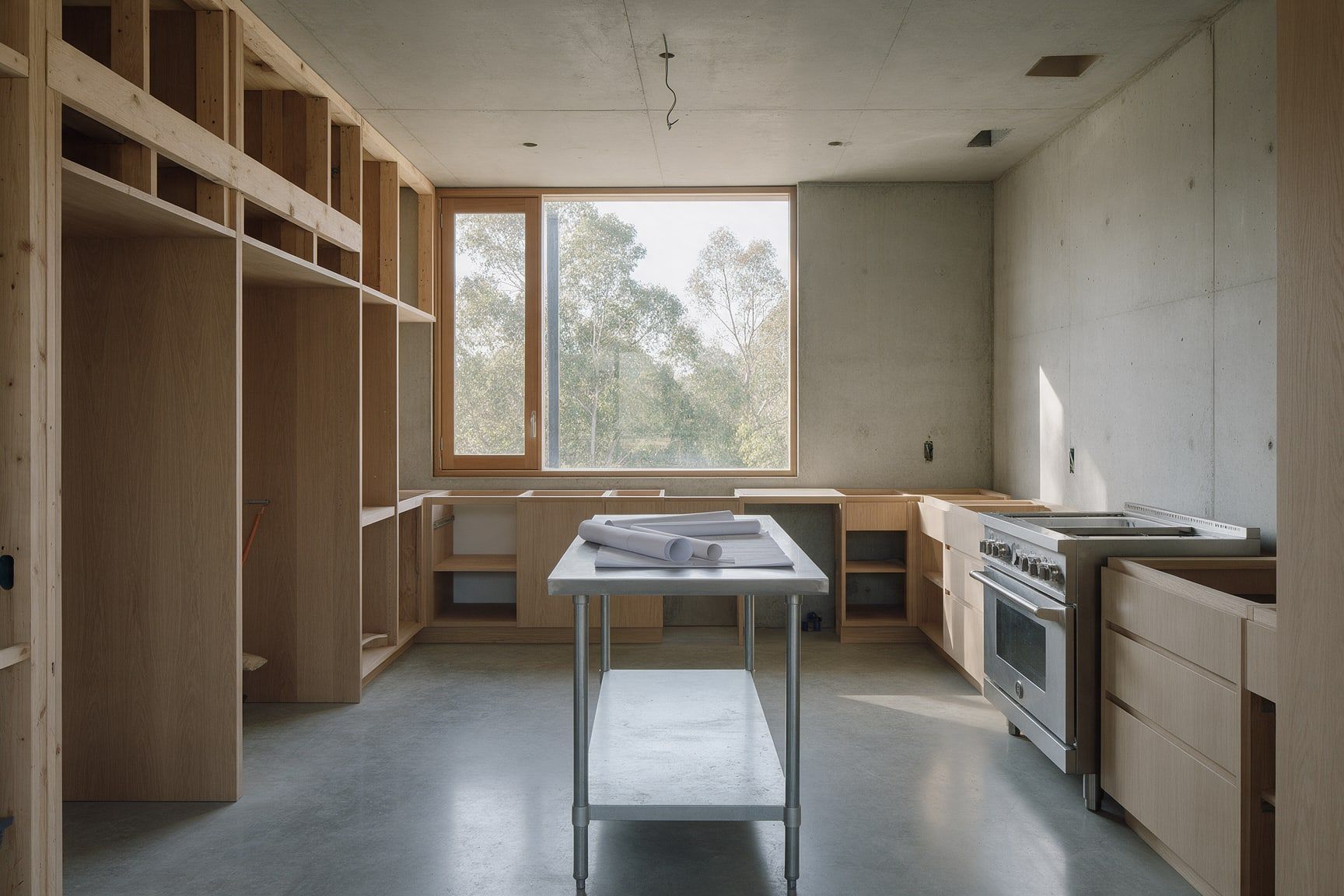 Espacio de cocina en obra con planos y acabados de concreto y madera, imagen conceptual.